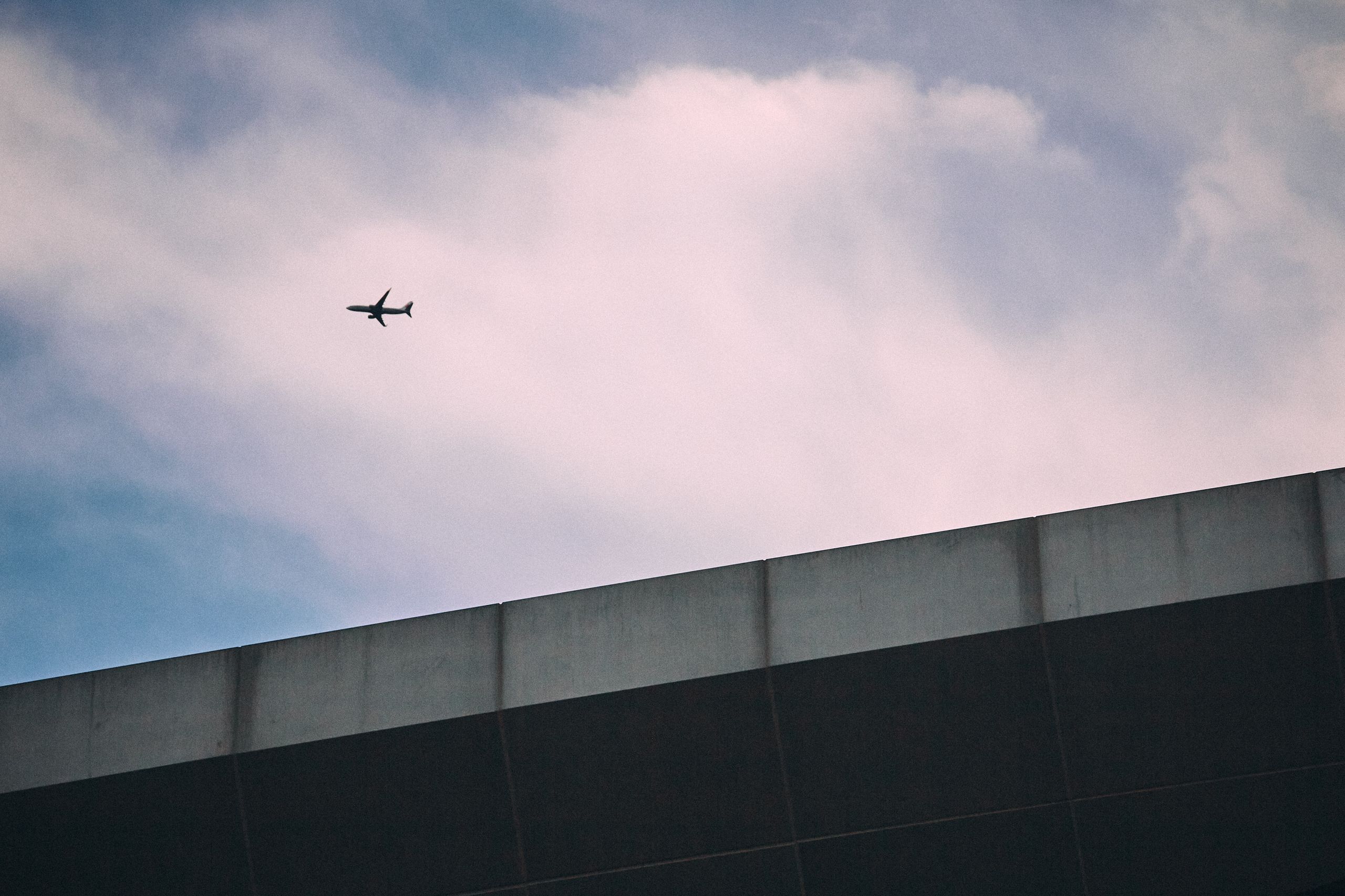 Aerial view of an airplane flying above modern architecture on a clear day. Perfect for travel themes.