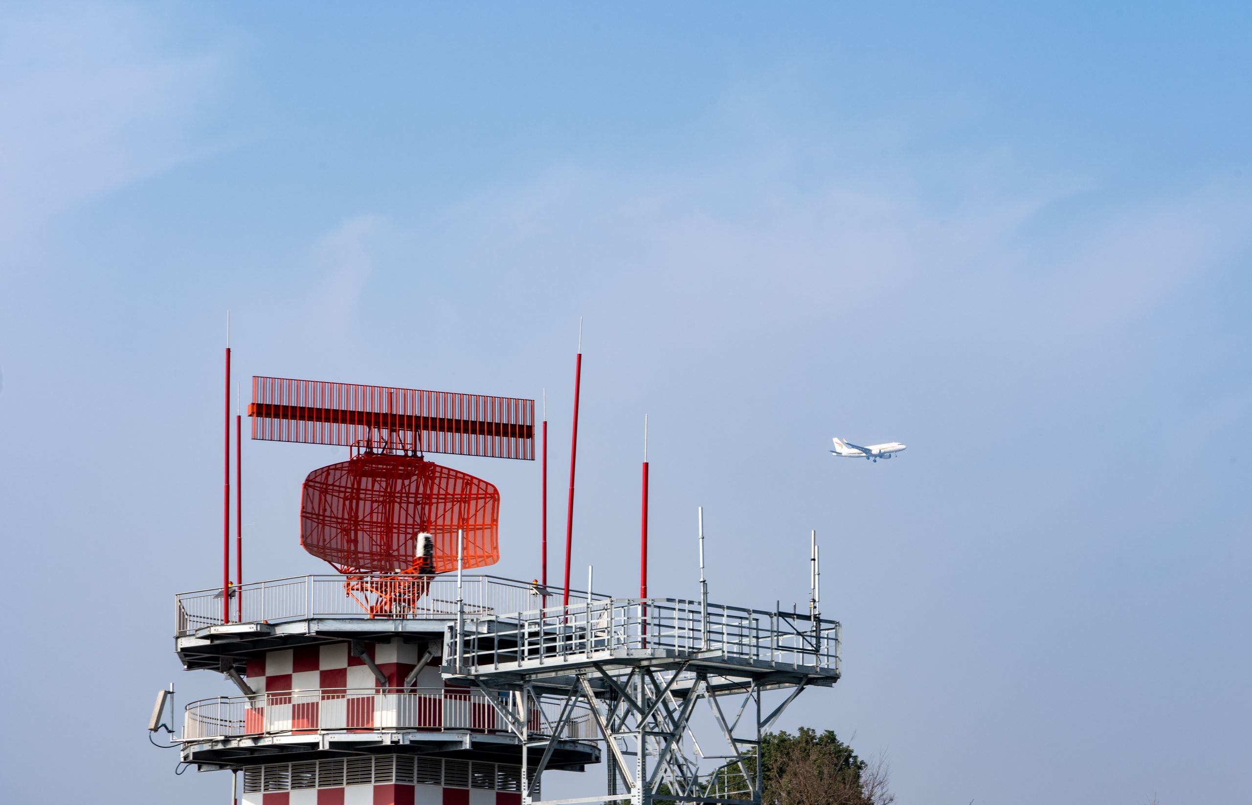 Radar tower and airplane in a blue sky, showcasing aviation technology